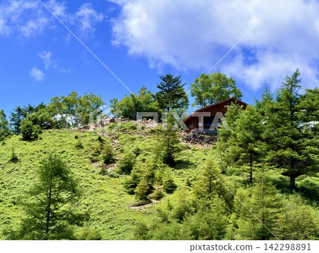 從東京最高峰雲取山頂眺望富士山和夏季山景,周圍環繞著藍天和積雲,以及雲取山避難小屋。 從東京最高峰雲取山頂眺望富士山和夏季山景,周圍環繞著藍天和積雲,以及雲取山避難小屋。 142298891