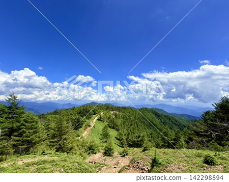 從東京最高峰雲取山頂眺望富士山和夏季山景,周圍環繞著藍天和積雲,以及雲取山避難小屋。 從東京最高峰雲取山頂眺望富士山和夏季山景,周圍環繞著藍天和積雲,以及雲取山避難小屋。 142298894