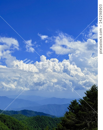 從東京最高峰雲取山頂眺望富士山和夏季山景，周圍環繞著藍天和積雲，以及雲取山避難小屋。 142298903