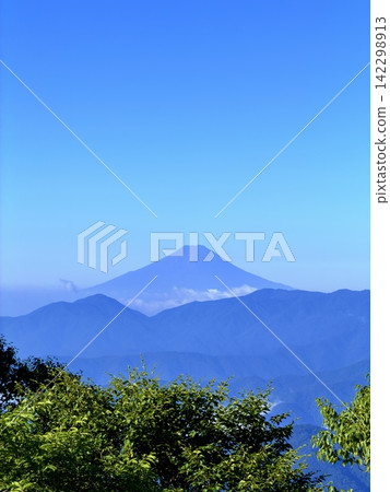 從東京最高峰雲取山頂眺望富士山和夏季山景,周圍環繞著藍天和積雲,以及雲取山避難小屋。 從東京最高峰雲取山頂眺望富士山和夏季山景,周圍環繞著藍天和積雲,以及雲取山避難小屋。 142298913
