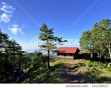 從東京最高峰雲取山頂眺望富士山和夏季山景，周圍環繞著藍天和積雲，以及雲取山避難小屋。 142298915
