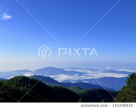 從東京最高峰雲取山頂眺望富士山和夏季山景,周圍環繞著藍天和積雲,以及雲取山避難小屋。 從東京最高峰雲取山頂眺望富士山和夏季山景,周圍環繞著藍天和積雲,以及雲取山避難小屋。 142298916