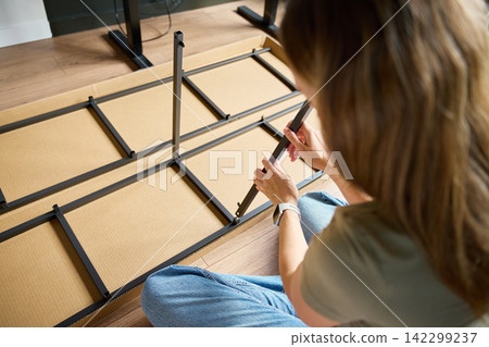 Woman Connecting Parts of a Metal Shelving Unit at Home Woman Connecting Parts of a Metal Shelving Unit at Home 142299237