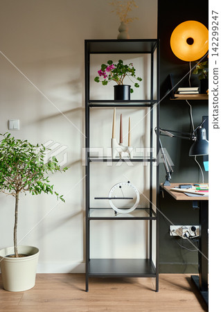 Tall shelf with plants and decor beside home office desk Tall shelf with plants and decor beside home office desk 142299247