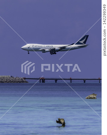 A vertical shot of a large cargo plane against the clear blue sky and sea of Shimoji Island. A vertical shot of a large cargo plane against the clear blue sky and sea of Shimoji Island. 142299349
