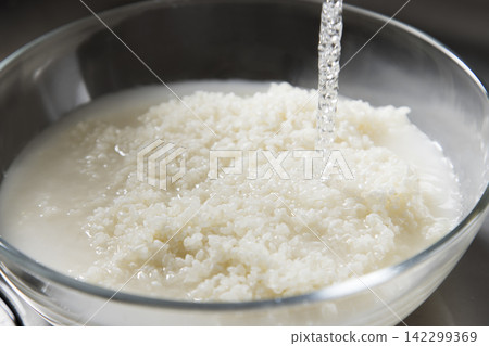A scene where water is added to rice in a bowl. A scene where water is added to rice in a bowl. 142299369