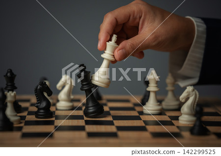 business hand holding white chess king taking black king, checkmate concept 142299525