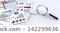 A printed document with business data and a magnifying glass 142299636