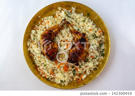 Delicious fried rice served with roasted chicken leg roast on traditional brass plate. Spicy chicken roast rice dish for lunch menu. Top view. Delicious fried rice served with roasted chicken leg roast on traditional brass plate. Spicy chicken roast rice dish for lunch menu. Top view. 142300459
