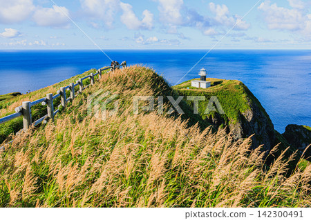 A breathtaking view of the Motochi Lighthouse on Rebun Island in Rishiri-Rebun-Sarobetsu National Park, surrounded by a clear summer sky and the blue sea. A breathtaking view of the Motochi Lighthouse on Rebun Island in Rishiri-Rebun-Sarobetsu National Park, surrounded by a clear summer sky and the blue sea. 142300491