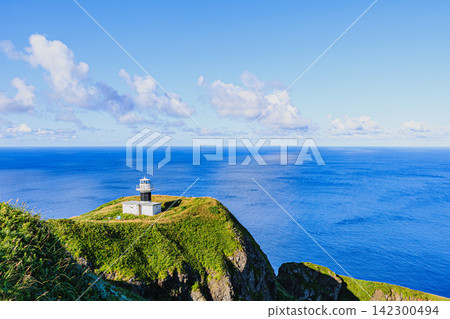 The white Motochi Lighthouse stands on a cape, as seen from the Momoiwa Observatory course on Rebun Island in Rishiri-Rebun-Sarobetsu National Park. The white Motochi Lighthouse stands on a cape, as seen from the Momoiwa Observatory course on Rebun Island in Rishiri-Rebun-Sarobetsu National Park. 142300494