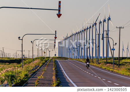 The Otonrui Wind Power Plant in Horonobe Town, bathed in the soft evening light, and a motorcycle traveling along a straight road. The Otonrui Wind Power Plant in Horonobe Town, bathed in the soft evening light, and a motorcycle traveling along a straight road. 142300505