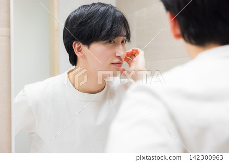 Young man looking in the mirror in the bathroom Young man looking in the mirror in the bathroom 142300963