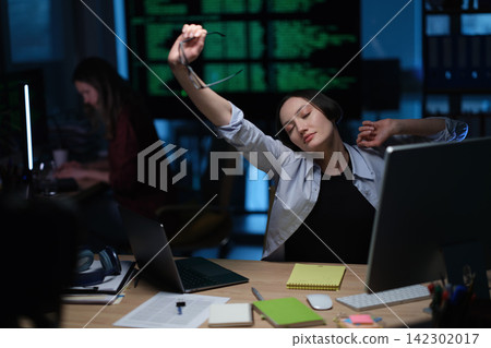 Tired businesswoman stretches arms during late office work Tired businesswoman stretches arms during late office work 142302017