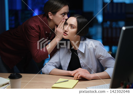 Business woman whispers private information to office colleague Business woman whispers private information to office colleague 142302046