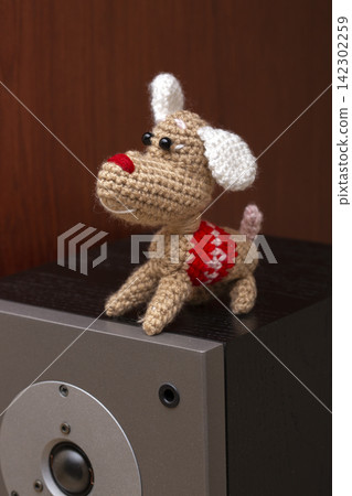 A knitted wool dog stands on a speaker. A knitted wool dog stands on a speaker. 142302259