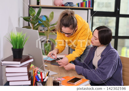 Pair of women review document during office work session Pair of women review document during office work session 142302596