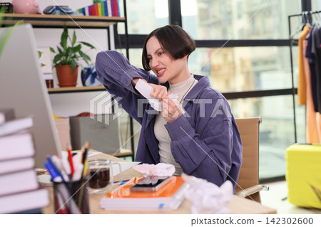 Angry woman tears documents while sitting at office desk Angry woman tears documents while sitting at office desk 142302600