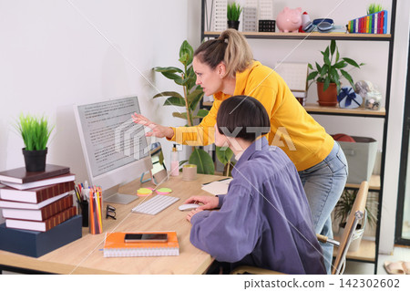 Pair of women collaborate at computer during office work session 142302602