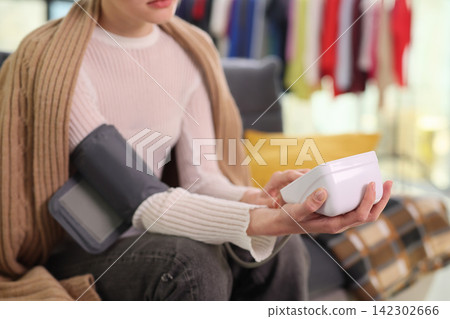 Woman checks blood pressure with digital monitor while resting Woman checks blood pressure with digital monitor while resting 142302666
