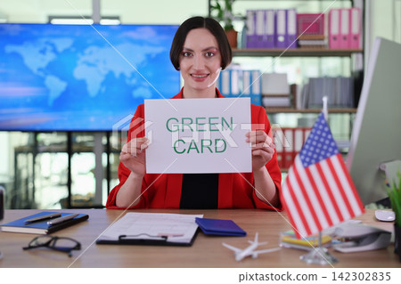 Embassy employee smiles warmly holding card with words Green Card Embassy employee smiles warmly holding card with words Green Card 142302835