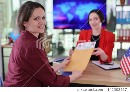 Woman receives visa documents from clerk at consular office Woman receives visa documents from clerk at consular office 142302837