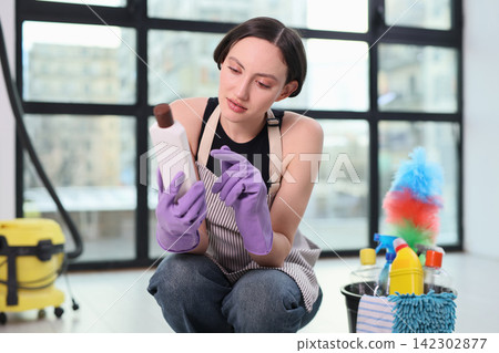 Young woman in gloves and apron reads detergent ingredients list Young woman in gloves and apron reads detergent ingredients list 142302877