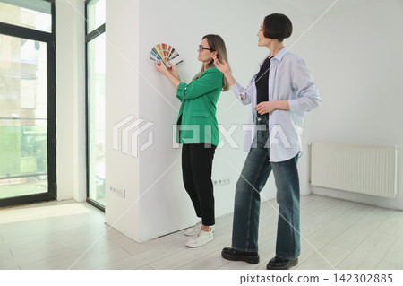 Designer attaches swatch palette to wall as client chooses style Designer attaches swatch palette to wall as client chooses style 142302885