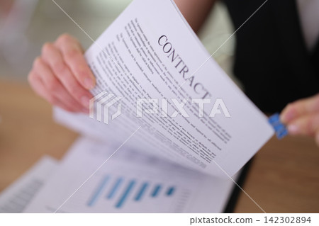 Businesswoman organizes contract pages with blue binder clip Businesswoman organizes contract pages with blue binder clip 142302894