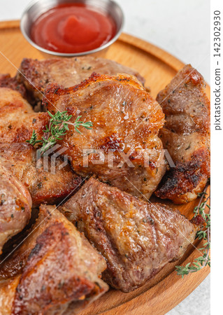 Grilled meat slices arranged on a wooden plate with a small bowl of ketchup and fresh thyme garnish, showcasing a delicious culinary presentation Grilled meat slices arranged on a wooden plate with a small bowl of ketchup and fresh thyme garnish, showcasing a delicious culinary presentation 142302930