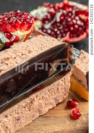Pate served in aluminum container garnished with pomegranate seeds and rosemary on wooden cutting board, with blurred pomegranate in the background Pate served in aluminum container garnished with pomegranate seeds and rosemary on wooden cutting board, with blurred pomegranate in the background 142303116