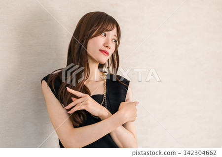 一張優雅的時尚肖像照，照片中的女士穿著黑色服裝，戴著珠寶。 142304662