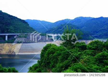 A dam lake and bridge in a mountainous area with a lowered water level. A dam lake and bridge in a mountainous area with a lowered water level. 142305206