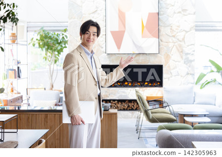 一名男性房地產銷售員面帶微笑，在樣品屋內帶領參觀並進行推銷。 142305963