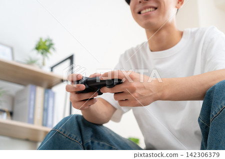 A young man playing video games at home A young man playing video games at home 142306379