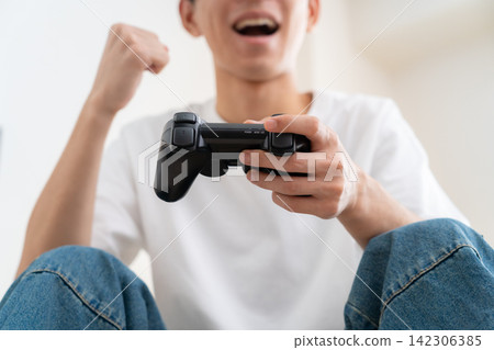 一個年輕人在家玩電子遊戲 142306385