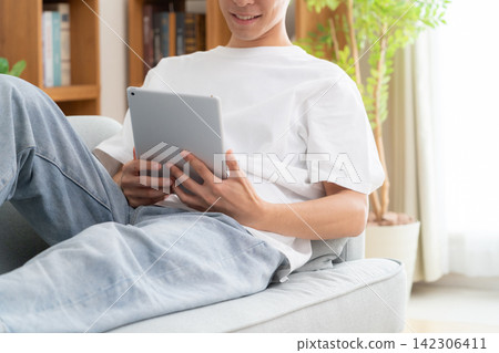 一位年輕男子在家看平板電腦 142306411