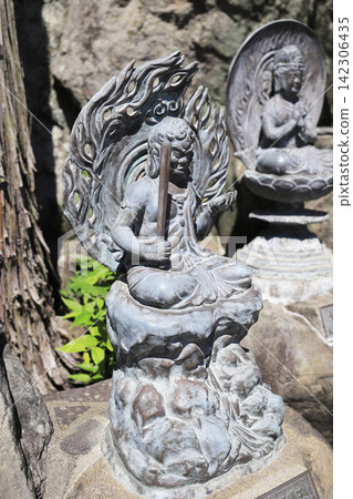 A statue of Fudo Myoo (Acala) is located within the temple grounds, with a statue of Dainichi Nyorai (Vairocana Buddha) in the background. A statue of Fudo Myoo (Acala) is located within the temple grounds, with a statue of Dainichi Nyorai (Vairocana Buddha) in the background. 142306435