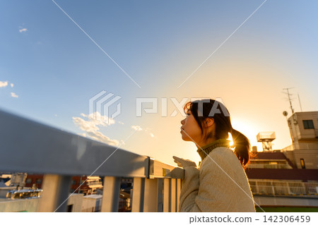 A woman looking at the setting sun A woman looking at the setting sun 142306459