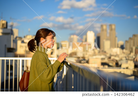 一位女子凝視遠方,背景是城市天際線。 一位女子凝視遠方,背景是城市天際線。 142306462