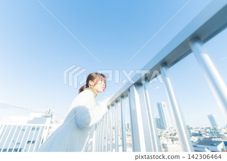 一名女子倚靠在欄桿上，仰望著天空。 142306464