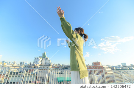 一位女子張開雙臂,伸向天空。 一位女子張開雙臂,伸向天空。 142306472
