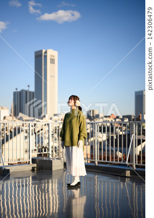 A woman standing on a balcony in a wintery city. A woman standing on a balcony in a wintery city. 142306479