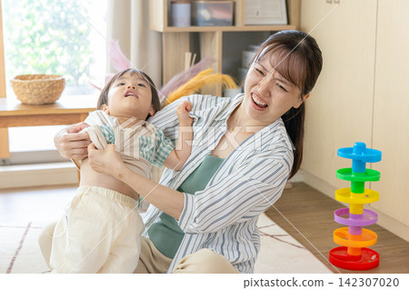 A mother is frustrated because she can't get her child dressed properly. A mother is frustrated because she can't get her child dressed properly. 142307020