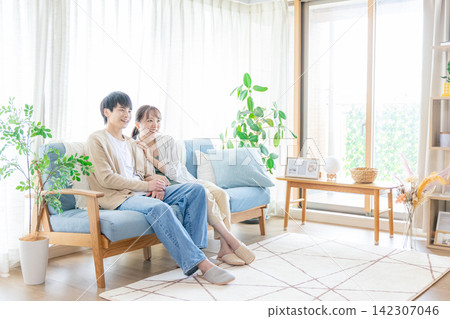 A couple sitting on the sofa in the living room A couple sitting on the sofa in the living room 142307046