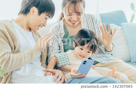 一個年輕的家庭，在智能手機上觀看視頻 142307065