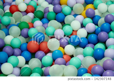 Detailed high angle close up shot of a massive pile of multicolored plastic balls in a children dry playground pool Detailed high angle close up shot of a massive pile of multicolored plastic balls in a children dry playground pool 142307148