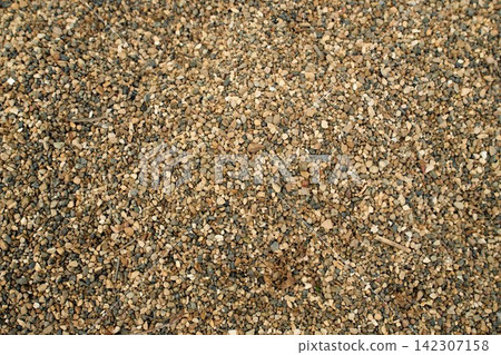 Continuous outdoor surface covered with medium-grain yellow-brown gravel mix and sand aggregate, daylight Continuous outdoor surface covered with medium-grain yellow-brown gravel mix and sand aggregate, daylight 142307158
