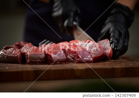 Chef cutting raw beef steak on wooden board Chef cutting raw beef steak on wooden board 142307409
