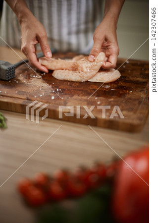 Hands preparing raw chicken breast on wooden board 142307466